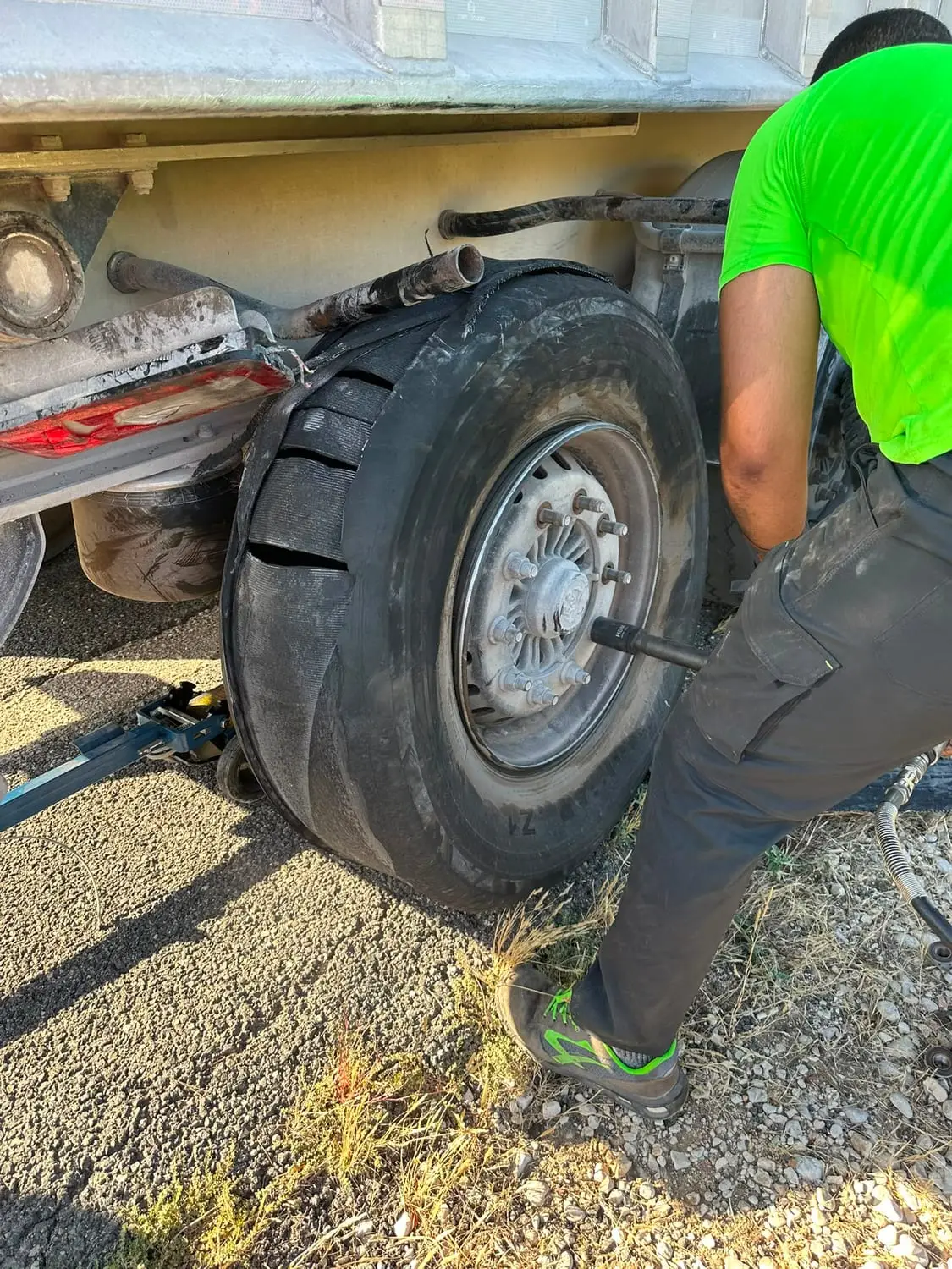 ZAC TRUCK mechanic using an impact wrench to remove a blown truck tyre at the roadside